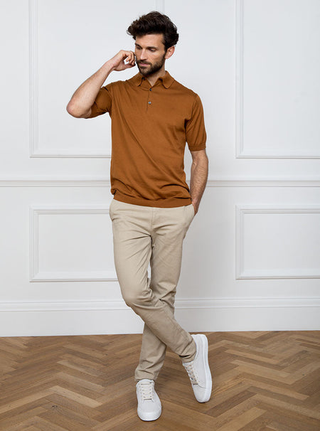 Man wearing ginger/burnt orange short sleeved polo sweater knit in 100% luxury and premium merino wool.